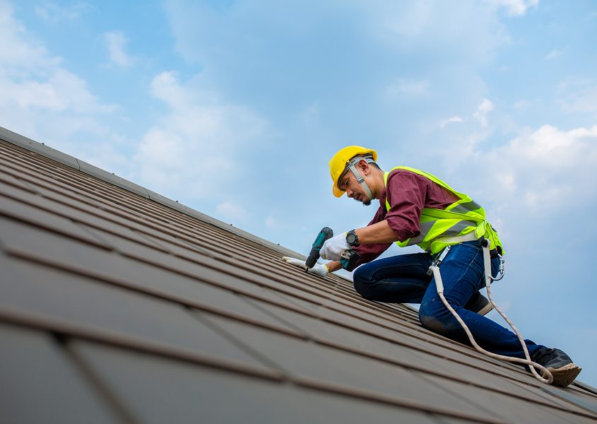 Roofing contractor installing shingles on a residential roof